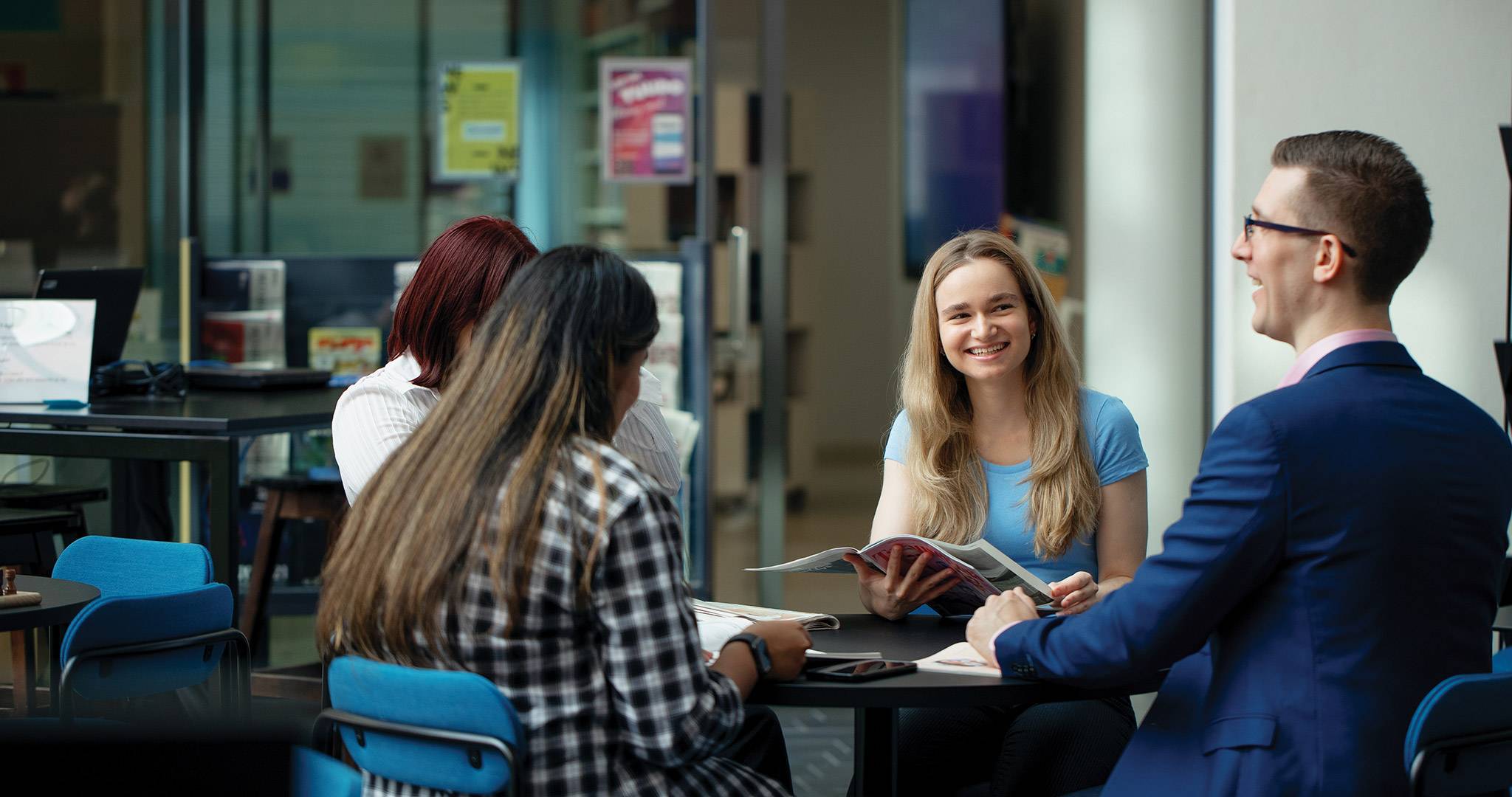 Four people sitting at a table discussing what they are reading.