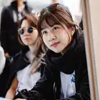 Woman at front looking to her right. Three blurred people in the background.