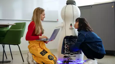 Två studenter programmerar en robot